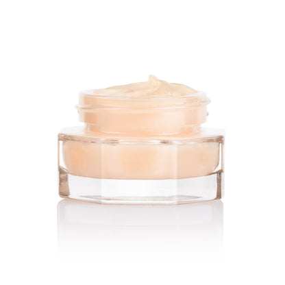 A closed, travel-sized thick and luscious dark champagne-coloured face cream in an open glass jar with a black and gold coloured lid next to it.