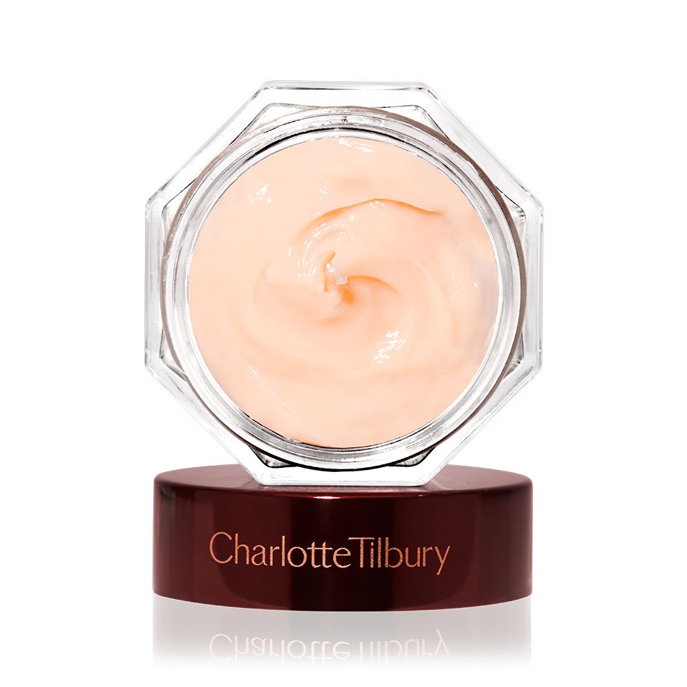 A thick and luscious dark champagne-coloured face cream in an open glass jar with a black and gold coloured lid next to it.