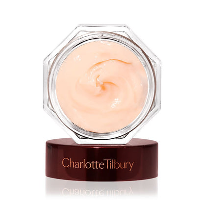 A thick and luscious dark champagne-coloured face cream in an open glass jar with a black and gold coloured lid next to it.