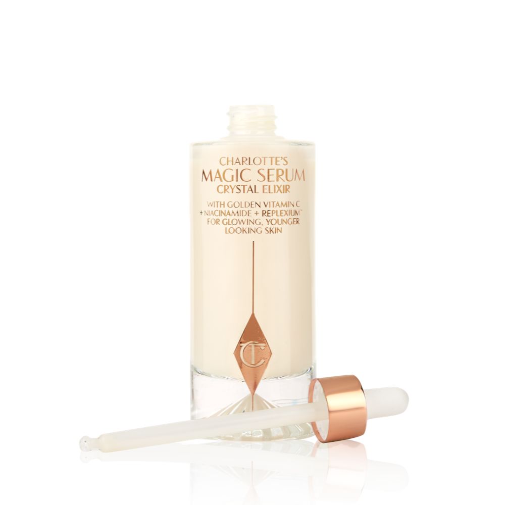 An open luminous, ivory-coloured serum in an opened glass bottle with its dropper beside it.