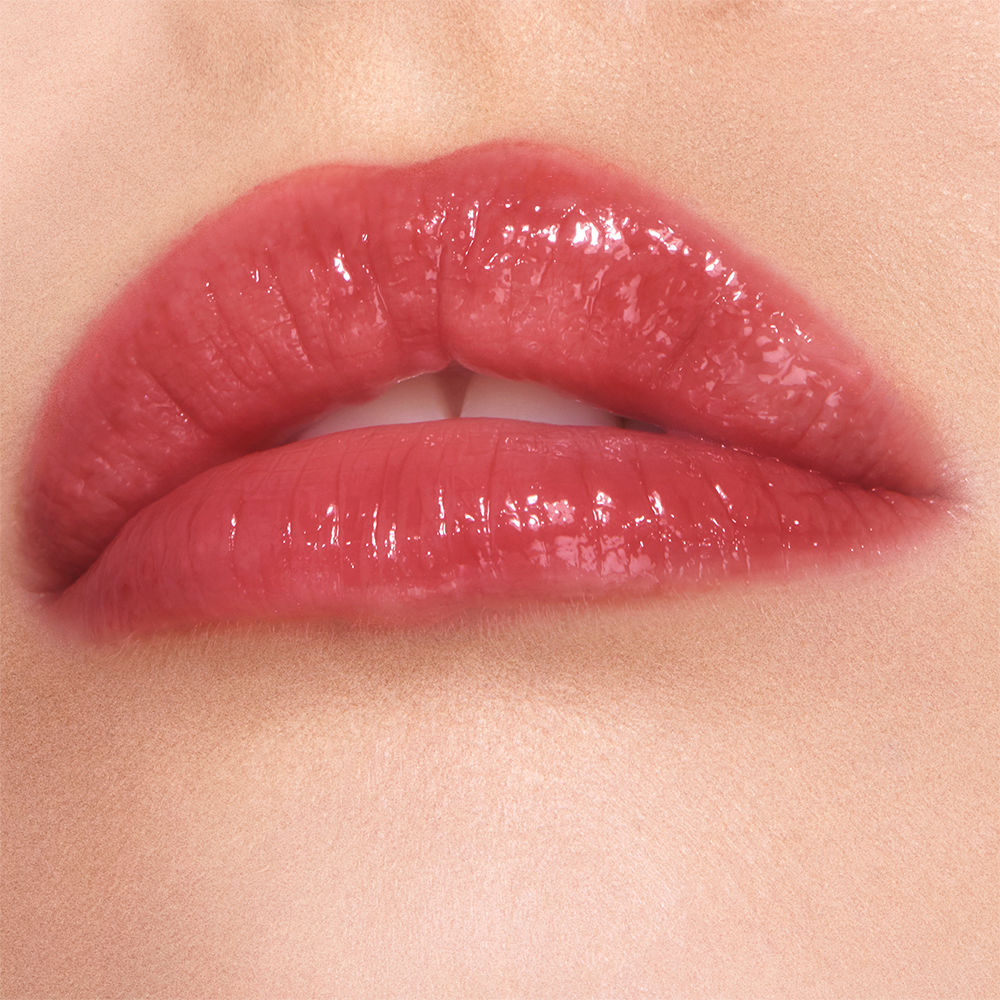 Lips close-up of a fair-tone model wearing a high-shine lip gloss in a berry-oink shade.