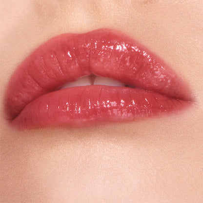 Lips close-up of a fair-tone model wearing a high-shine lip gloss in a berry-oink shade.