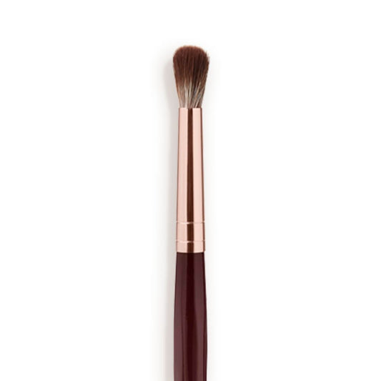 Close-up of an eyeshadow blending brush with soft bristles and a rose-gold and dark crimson handle.