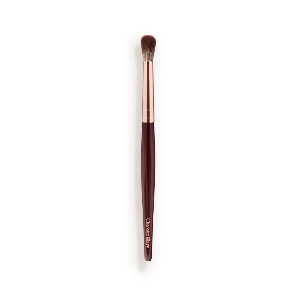 An eyeshadow blending brush with a golden and dark crimson-coloured handle.