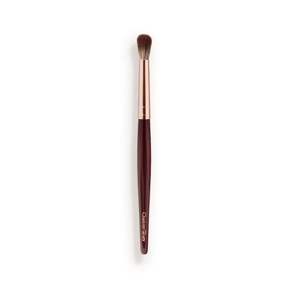 An eyeshadow blending brush with a golden and dark crimson-coloured handle.