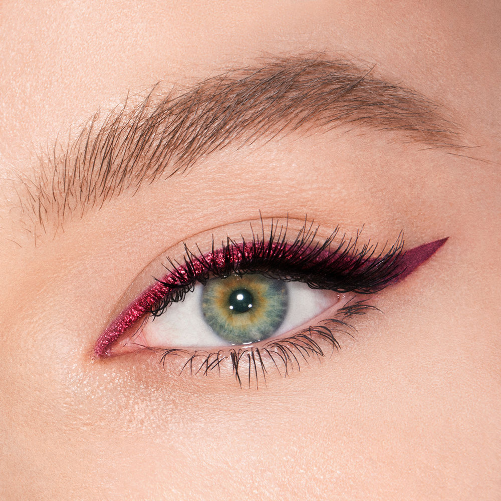 Fair-tone model with green eyes eye close-up of a sparkly maroon eyeliner with a soft wing in matte purple colour.
