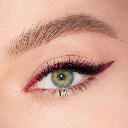 Fair-tone model with green eyes eye close-up of a sparkly maroon eyeliner with a soft wing in matte purple colour.
