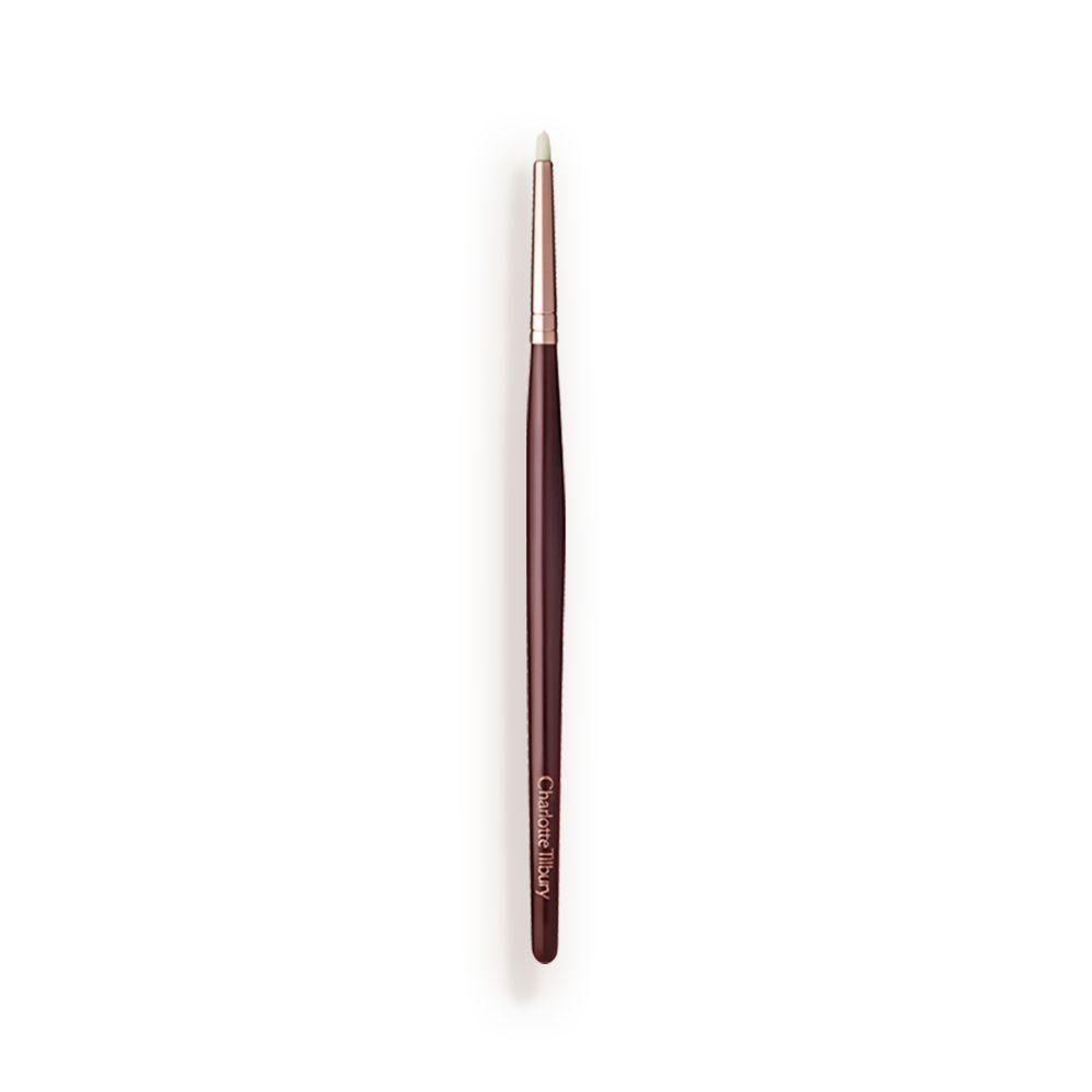 A slim eyeshadow brush with white-coloured bristles with a rose-gold and dark crimson handle.