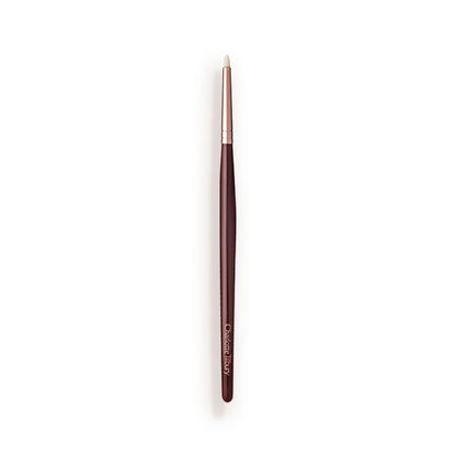 A slim eyeshadow brush with white-coloured bristles with a rose-gold and dark crimson handle.