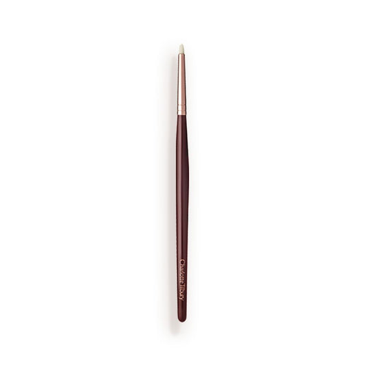 A slim eyeshadow brush with white-coloured bristles with a rose-gold and dark crimson handle.