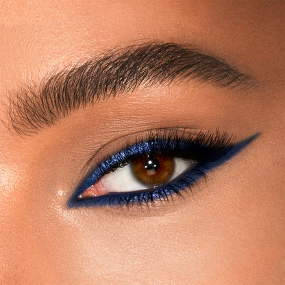 Medium-tone model eye close-up of shimmery cobalt blue eyeliner on the upper lid and lower water line.