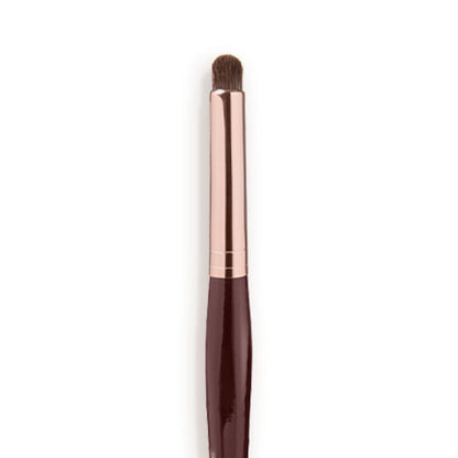 Close-up of an eyeshadow smudging brush with soft bristles and a rose-gold and dark crimson handle.