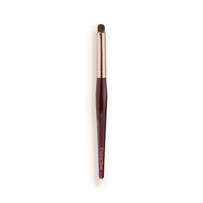 An eyeshadow smudging brush with soft bristles and rose gold and dark crimson handle.