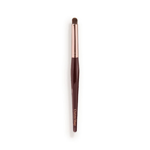 An eyeshadow smudging brush with soft bristles and rose gold and dark crimson handle.