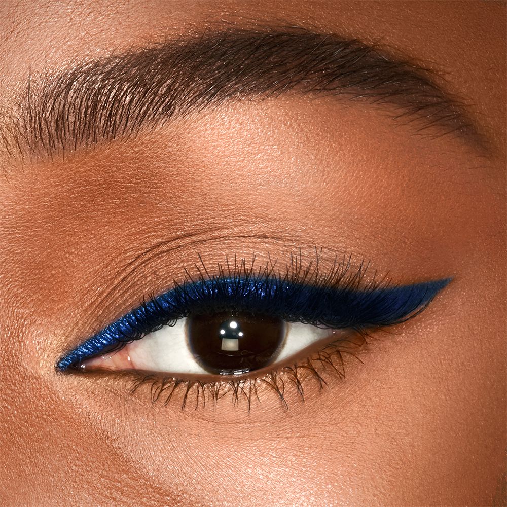 Eye close-up of a deep skin model with brown eyes wearing a vivid, royal blue eyeliner in a soft wing.
