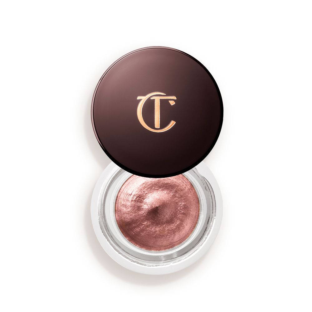 Cream eyeshadow in an open glass pot in a nude pink shade with fine shimmer, with the lid placed next to it.