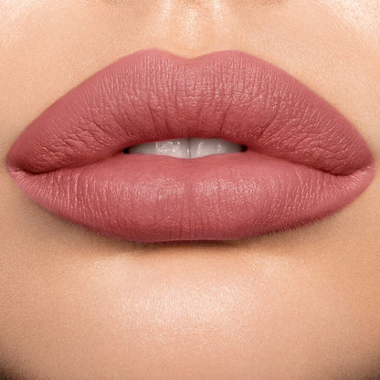 Lips close-up of a light skin model wearing a pigmented, matte lipstick in a rose-bud pink colour.