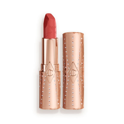 An open, golden peachy-pink lipstick in a metallic, golden-coloured tube with its lid next to it.