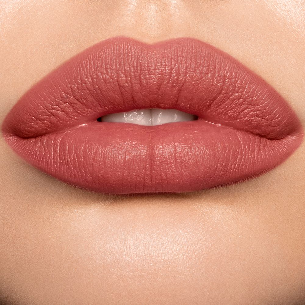 Lips close-up of a light skin model wearing a pigmented, matte lipstick in a golden peachy-pink colour.