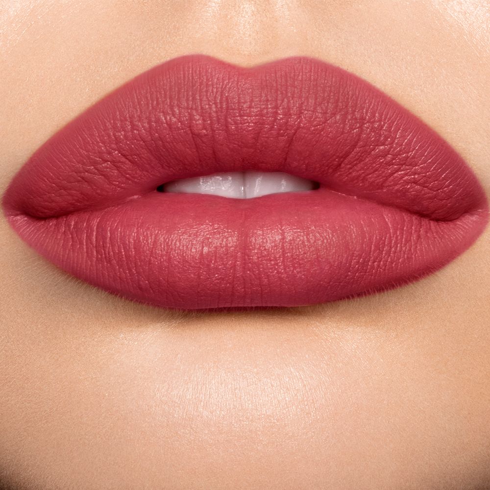 Lips close-up of a light skin model wearing a pigmented, matte lipstick in a blushed berry-rose colour.