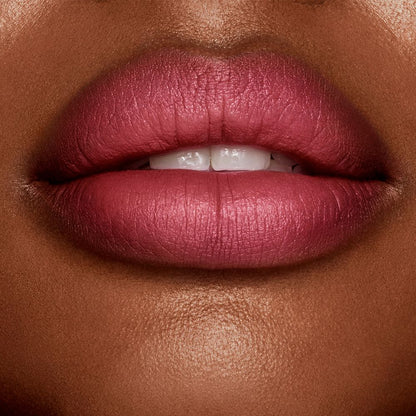 Lips close-up of a deep-tone model wearing a matte, berry-rose lipstick.