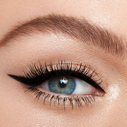 Single eye close-up of a fair-tone model with blue eyes wearing a duo eyeliner in black and champagne-beige on her upper lid and lower waterline.