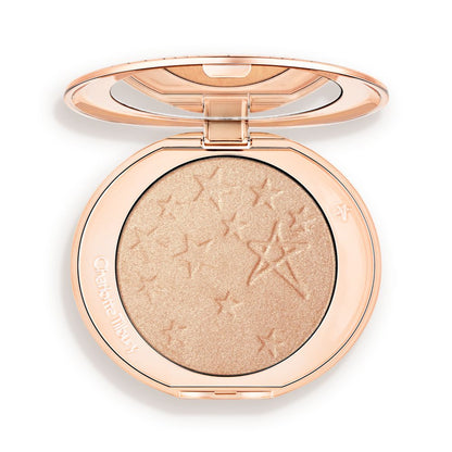 An open highlighter powder compact with a mirrored lid, in a shimmery champagne shade.