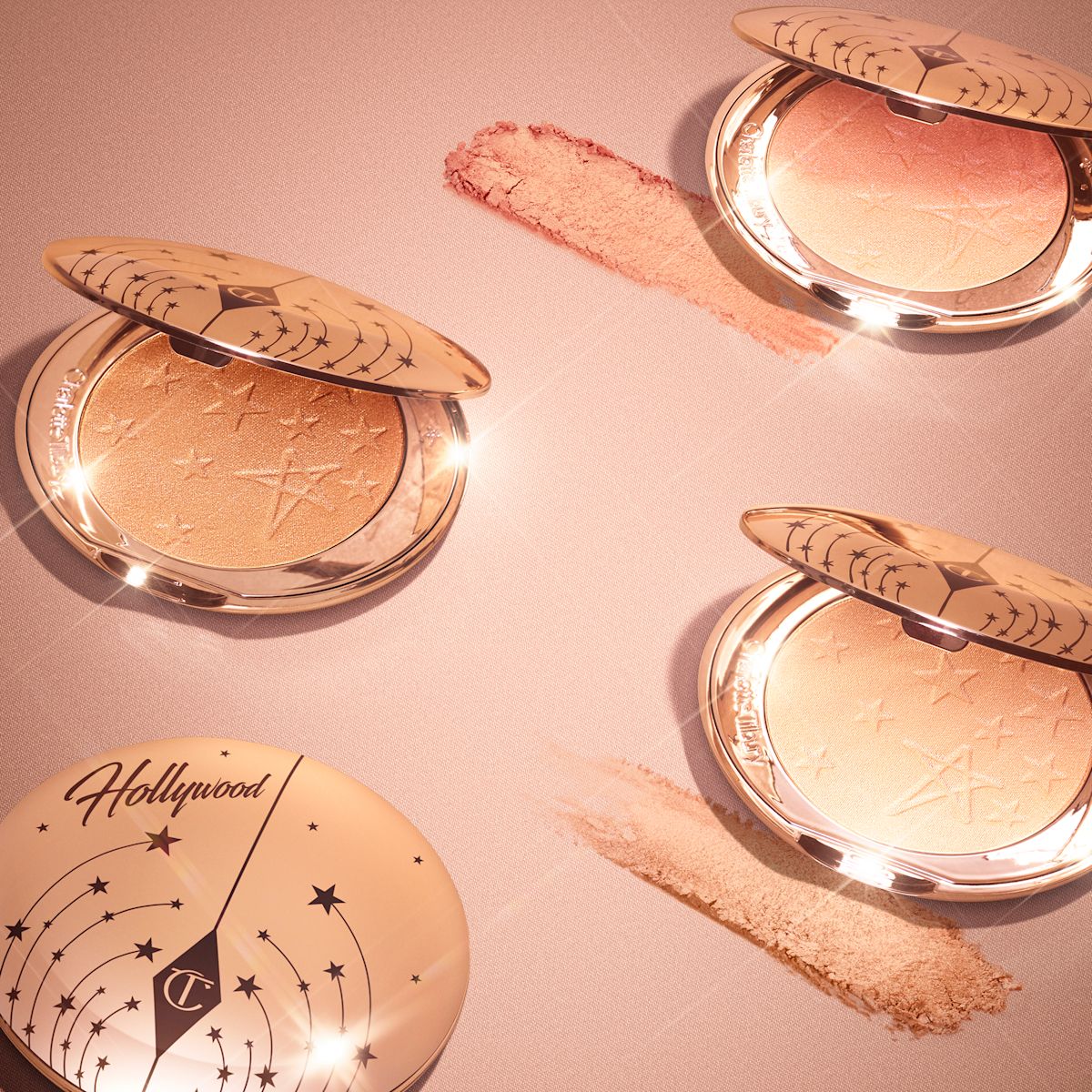 Collection of open, powder highlighter compacts in shades of gold, brown, pink, and silver in sleek, golden-coloured lids.