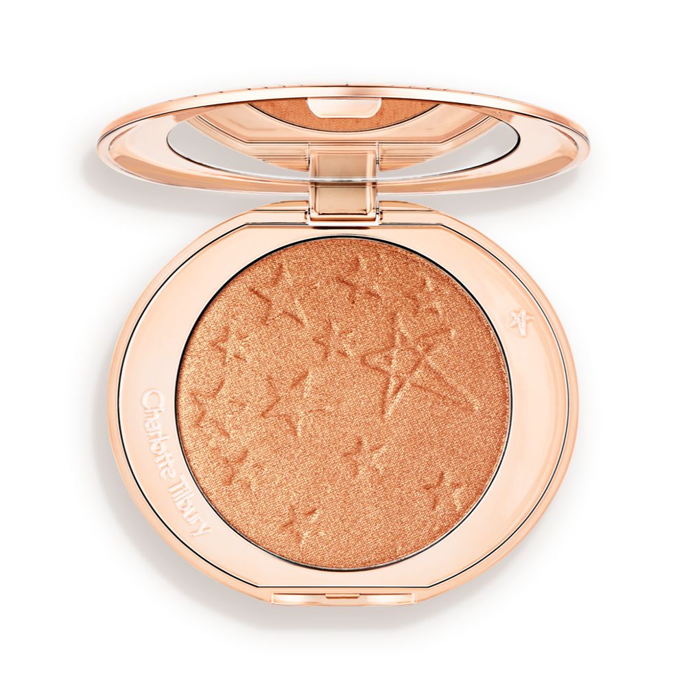 An open highlighter powder compact in a soft rose gold shade with a mirrored lid.