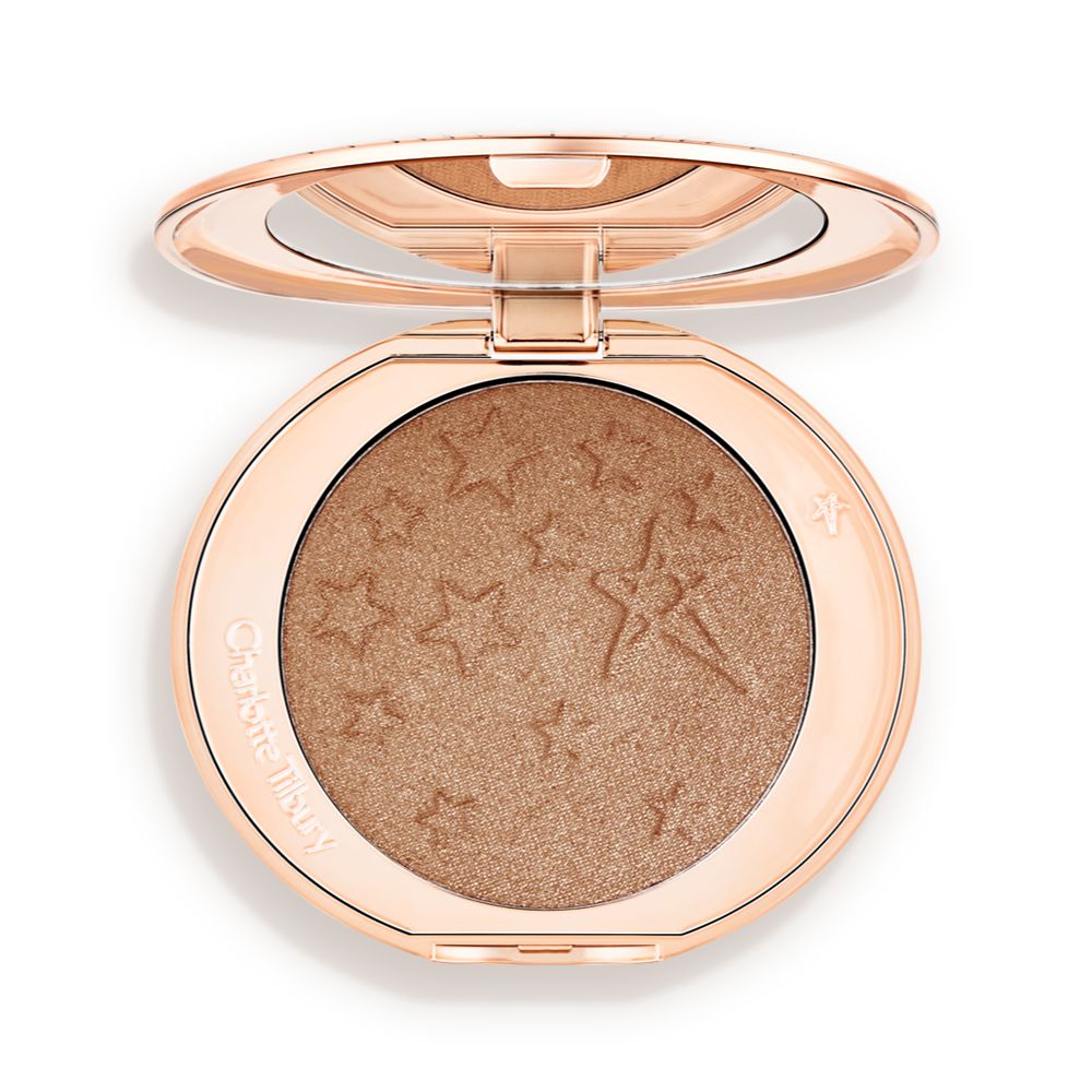 An open highlighter powder compact with a mirrored lid, in a shimmery bronze-gold shade.