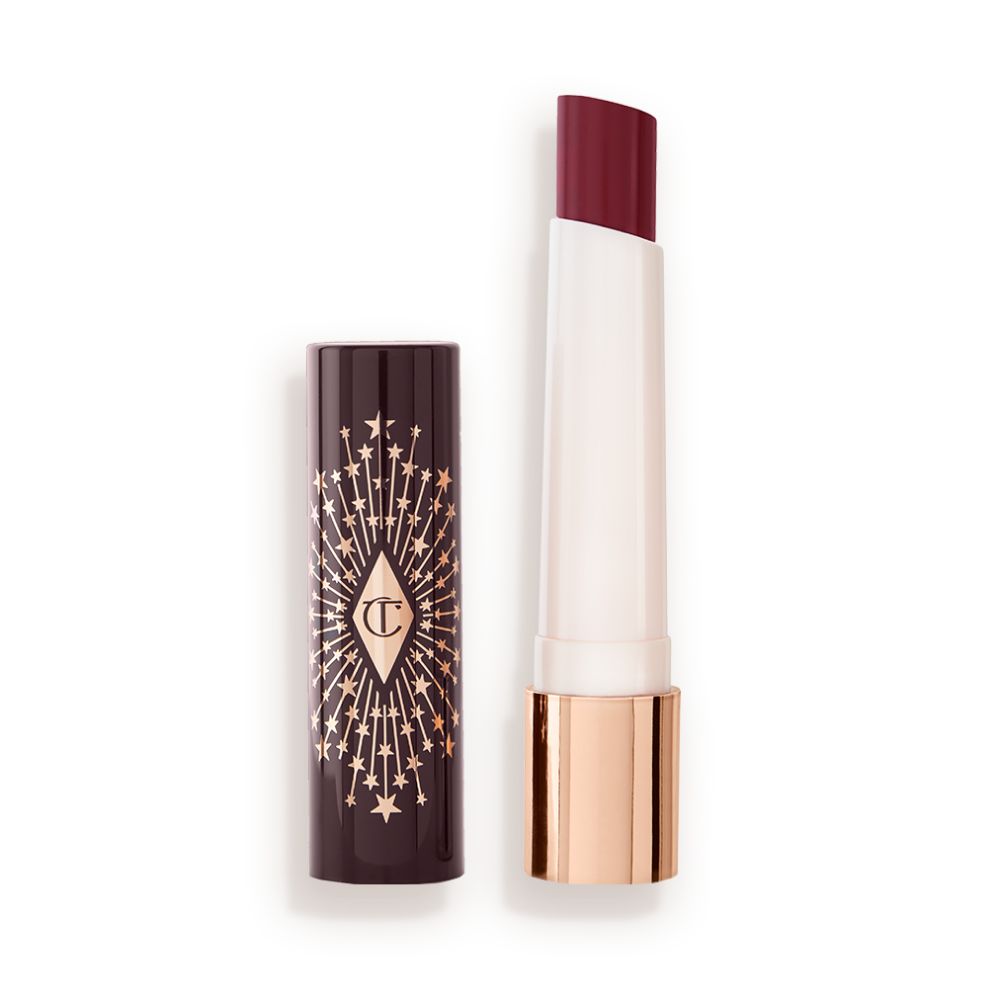 An open lipstick lip balm in a berry shade, in white and gold tube with a black-coloured lid with gold sparkles all over it.