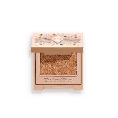 An open, single-pan eyeshadow with a mirrored lid in an iridescent orange-gold shade with very fine shimmer.