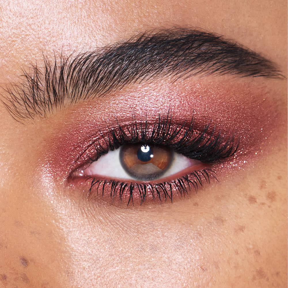 Close-up of a model with brown eyes wearing iridescent rustic red eyeshadow with very fine shimmer.