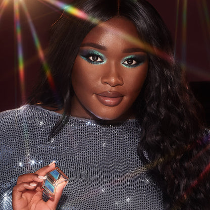 Deep-tone brunette model with brown eyes wearing iridescent duochrome purple and teal eyeshadow with very fine shimmer.