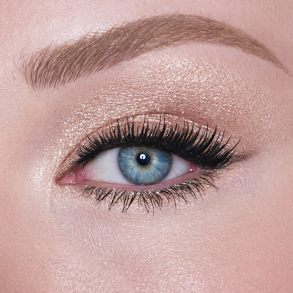 Single-eye close-up of a fair-tone model with blue eyes wearing an iridescent pearl eyeshadow with very fine shimmer.