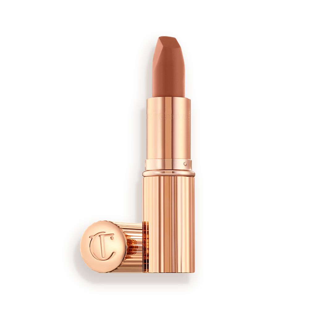 An open lipstick in a fresh, neutral nude peach matte shade, in a sleek, gold-coloured tube.
