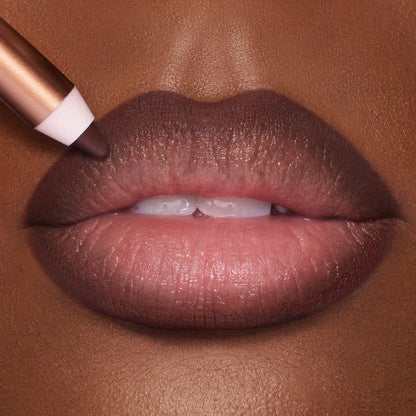 Close-up of a tanned model's lips that have a tawny-brown matte lip shade applied to them.