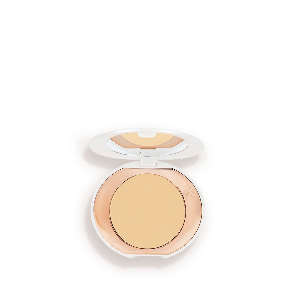 A miniature compact brightening powder in a white shade for tan and deep skin tones.