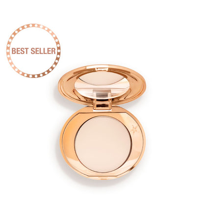 An open, mirrored-lid, mini, pressed powder compact in a cream colour.