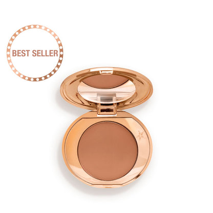 An open, mirrored-lid mini, pressed powder compact in a medium-brown shade, perfect for deep-tones.