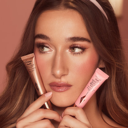 A fair skin model holding and wearing a liquid blush and liquid highligher