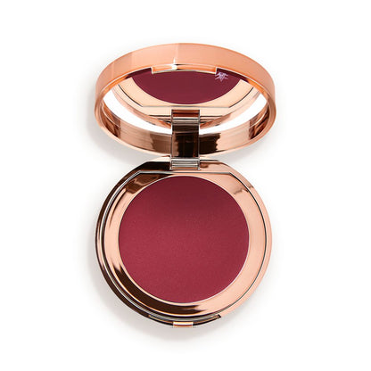 An open, mirrored-lid lip and cheek cream compact in a berry-red shade.
