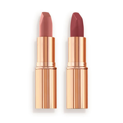 Two matte lipsticks, one a nude pink and the other a berry-rose shade in golden, metallic tubes with their lids removed.