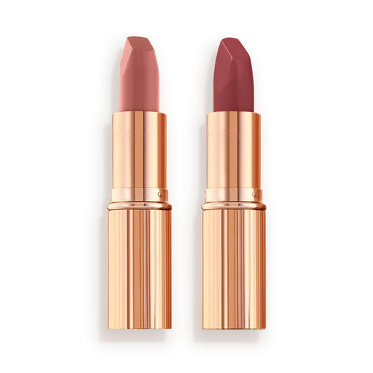Two matte lipsticks, one a nude pink and the other a berry-rose shade in golden, metallic tubes with their lids removed.