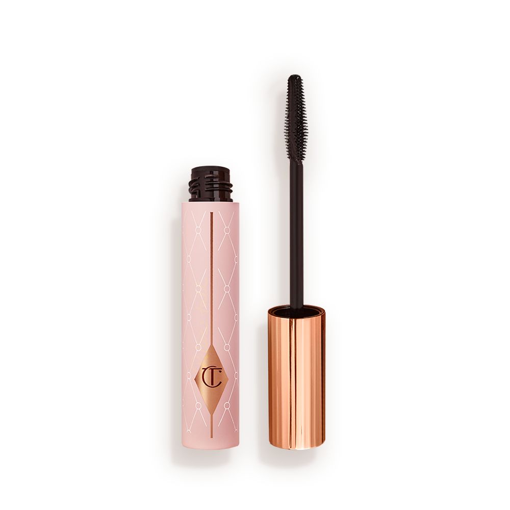 Mascara in a pink-coloured tube with its gold-coloured lid with a black applicator next to it.