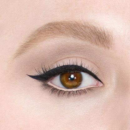 Close-up of a fair-tone model with brown eyes wearing blue-black eyeliner pencil on her eyelid and nude beige eyeliner pencil on her lower waterline.