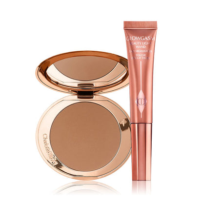 An open, mirrored-lid bonzer compact with a warm-brown bronzer and a highlighter-blush wand in a warm pink shade.