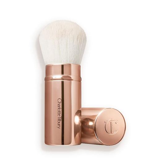 A face blending brush with white bristles in rose gold packaging with the cap beside it.