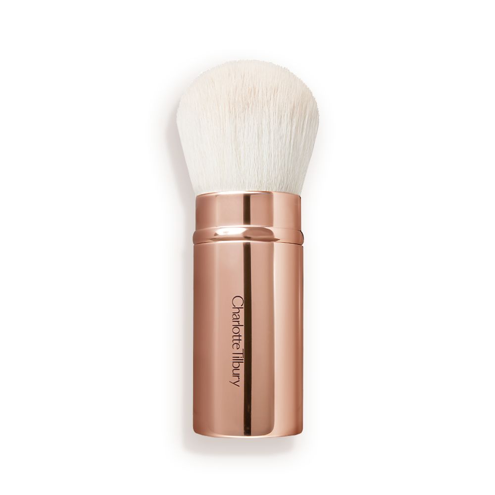 A face blending brush with white bristles in rose gold packaging.