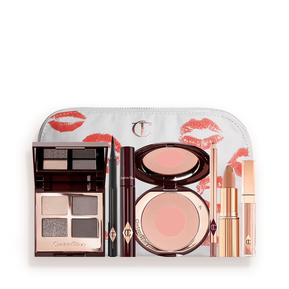 A makeup pouch with an open, mirrored-lid eyeshadow palette in matte and shimmery silver, grey, and beige shades, an open black eyeliner pen, a mascara in a dark-crimson colour scheme, a nude-pink lipstick with a matching lip liner pencil, nude pink lip gloss, and an open two-tone blush in muted rose-gold and pink.